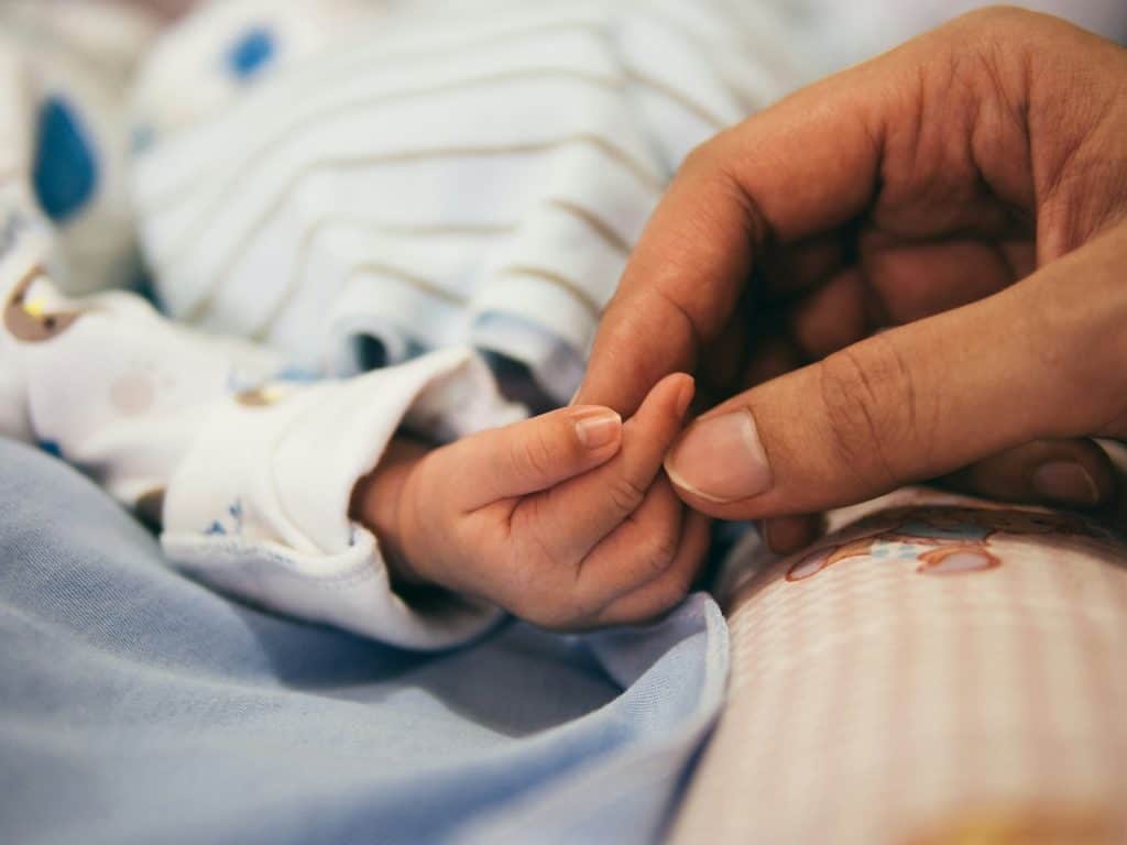 More than Mamas 2 person holding baby's index finger